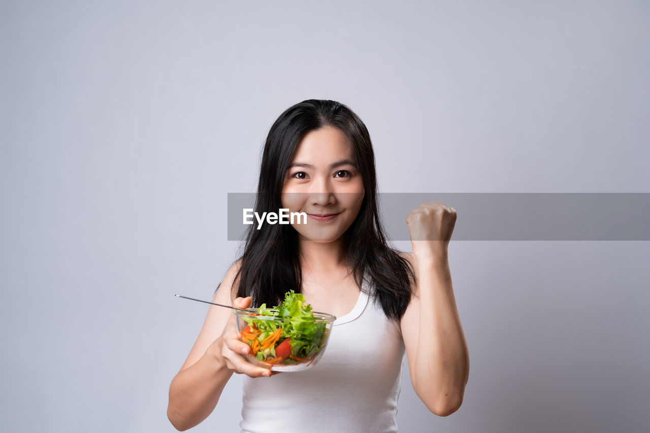 PORTRAIT OF A SMILING YOUNG WOMAN HOLDING ICE CREAM