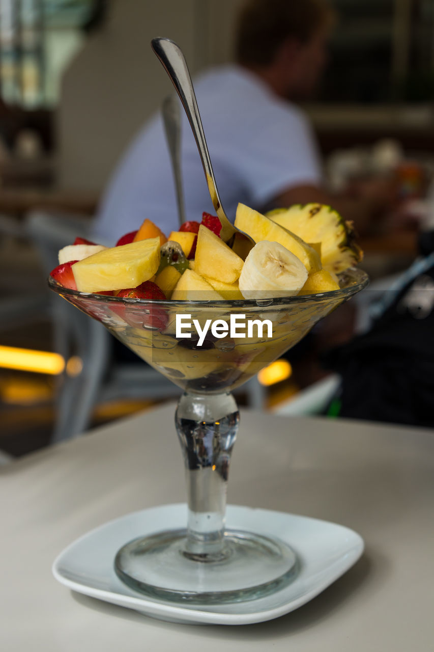 food and drink, food, fruit, cocktail, focus on foreground, glass, freshness, brunch, business, refreshment, alcohol, table, household equipment, drink, alcoholic beverage, meal, indoors, martini glass, restaurant, healthy eating, yellow, close-up, drinking glass, bar