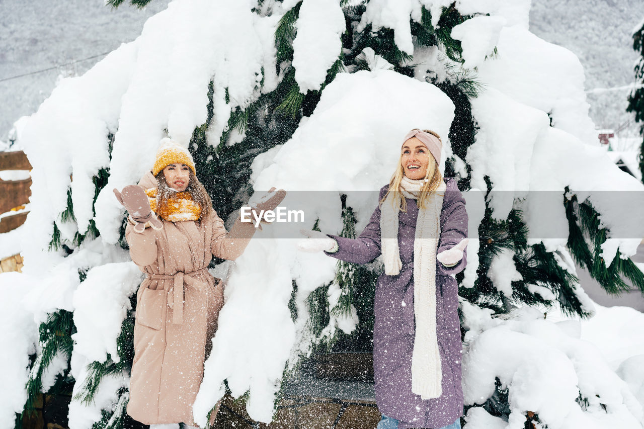 Two adult women friends are happy with the snow and have fun