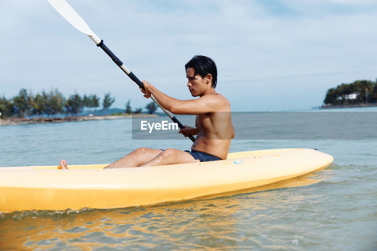 rear view of man kayaking in lake