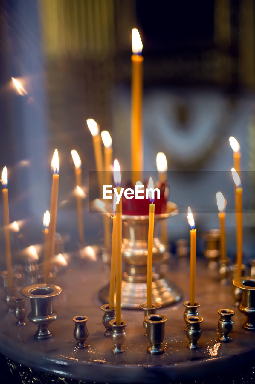 Yellow orange burning church candles in a candlestick