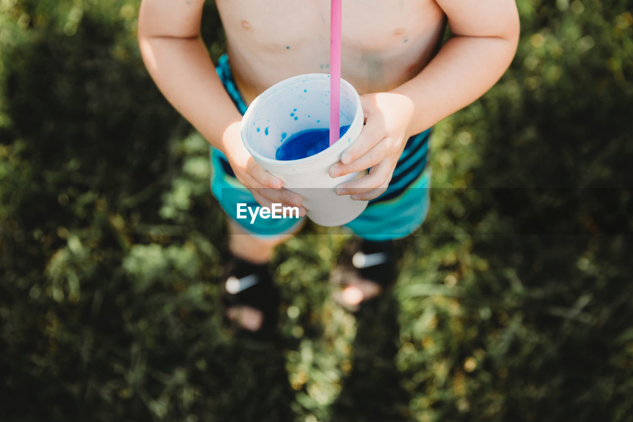 Above perspective of young boy drinkning blue snowcone