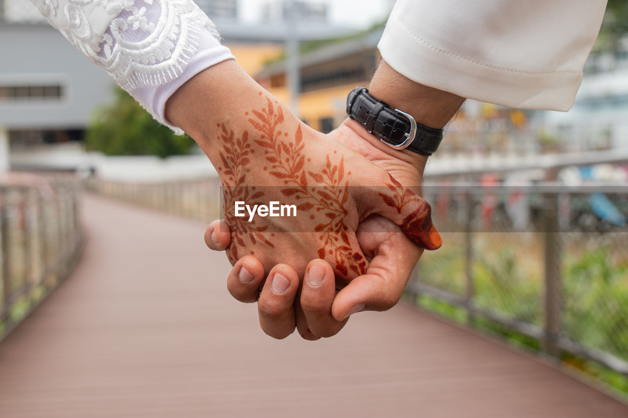 Midsection of couple holding hands