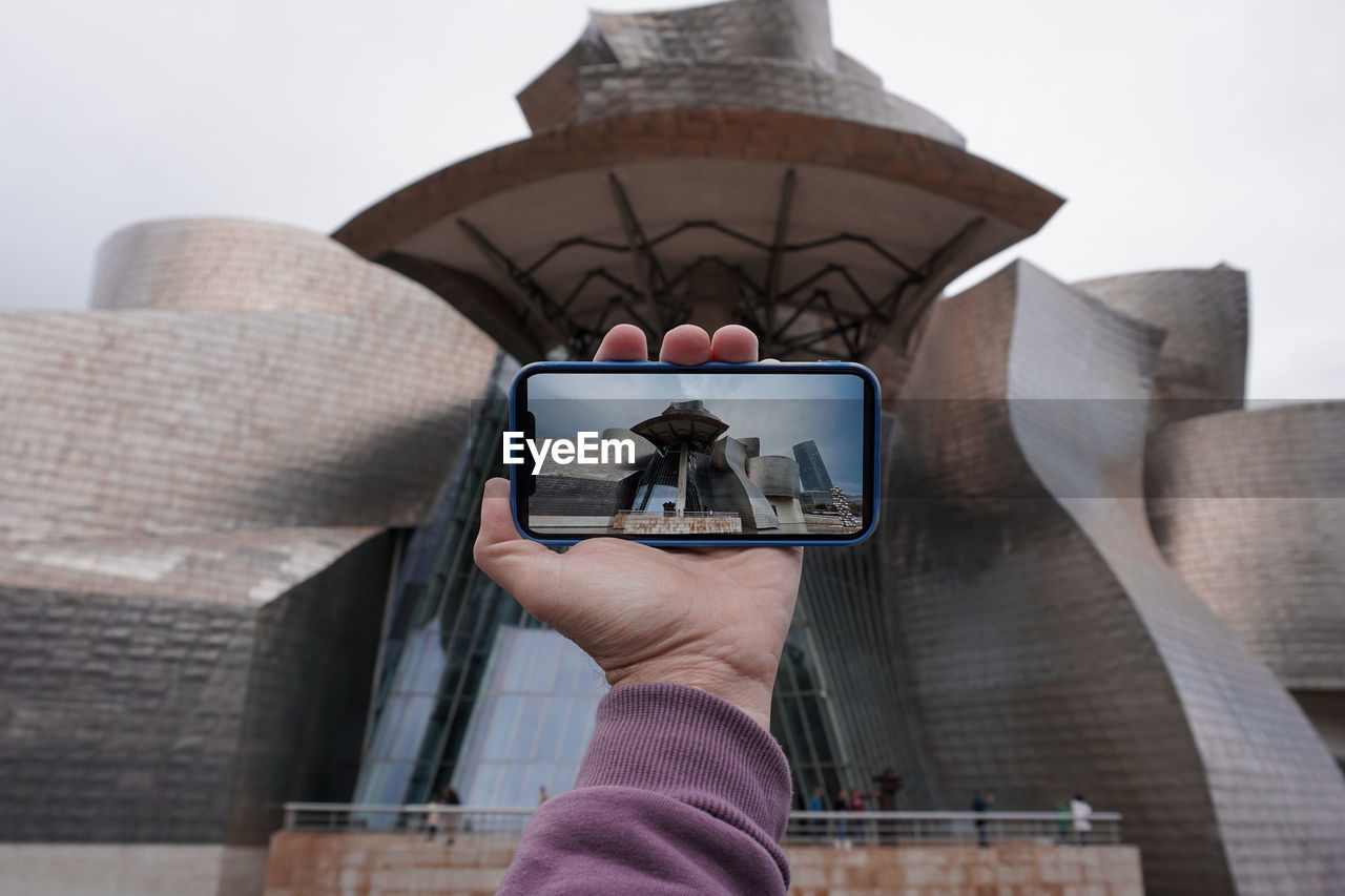 low angle view of woman using mobile phone against sky