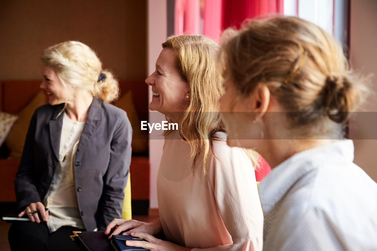 Smiling female entrepreneurs sitting in office seminar at workplace