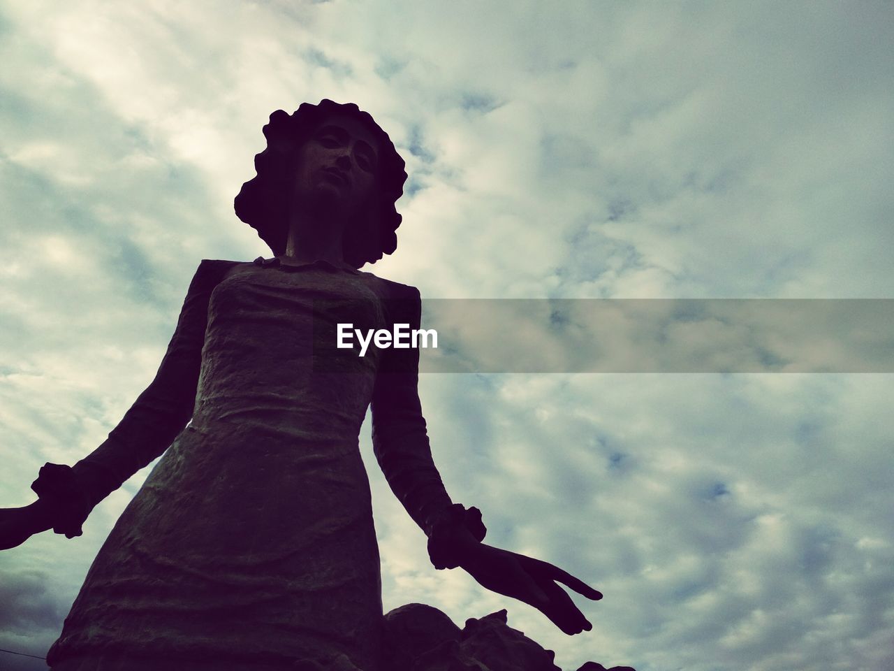 LOW ANGLE VIEW OF MAN STATUE AGAINST CLOUDY SKY