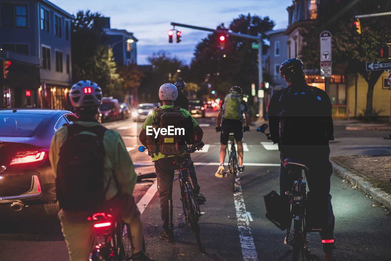 REAR VIEW OF PEOPLE RIDING BICYCLE ON ROAD