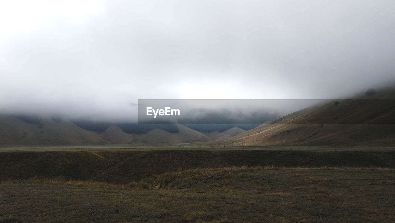 Scenic view of field and mountains against sky