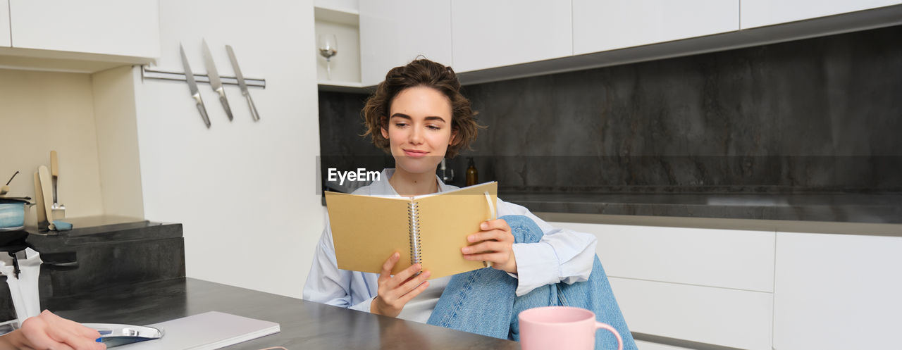 portrait of young woman using digital tablet while sitting on table