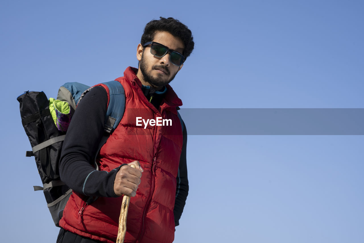 Young indian traveler boy trekking over a rocky mountain, standing on the top of the mountain