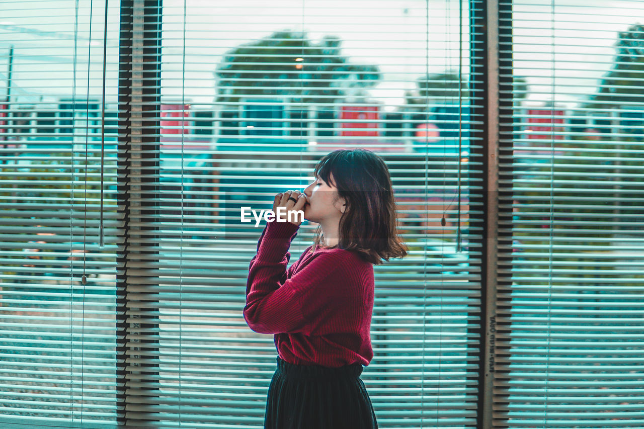 Young woman looking through window