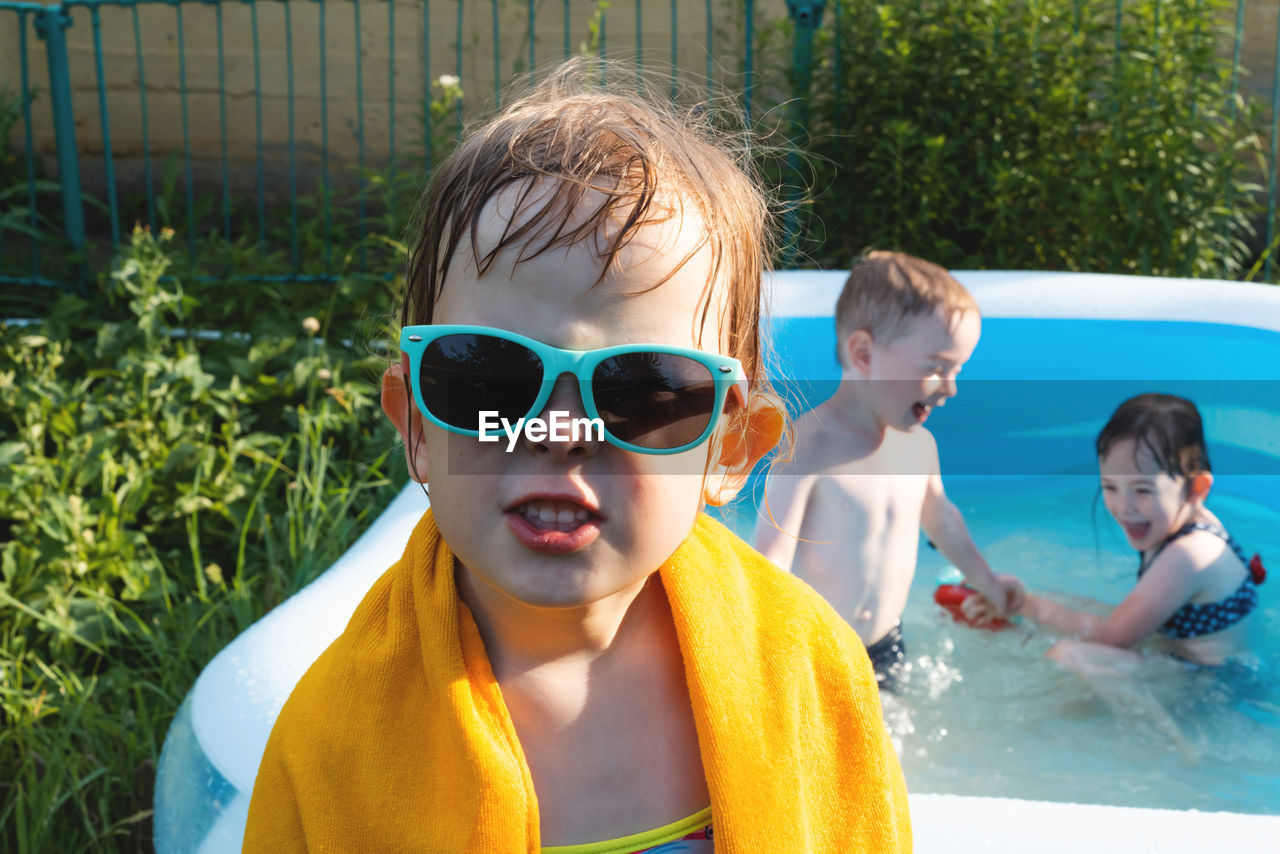 Wet and cheerful child in a towel and sunglasses near the pool. summer is a time of pleasure and fun