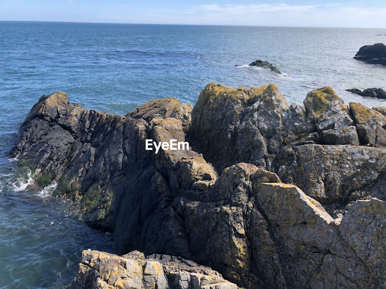 Rocks on shore by sea against sky