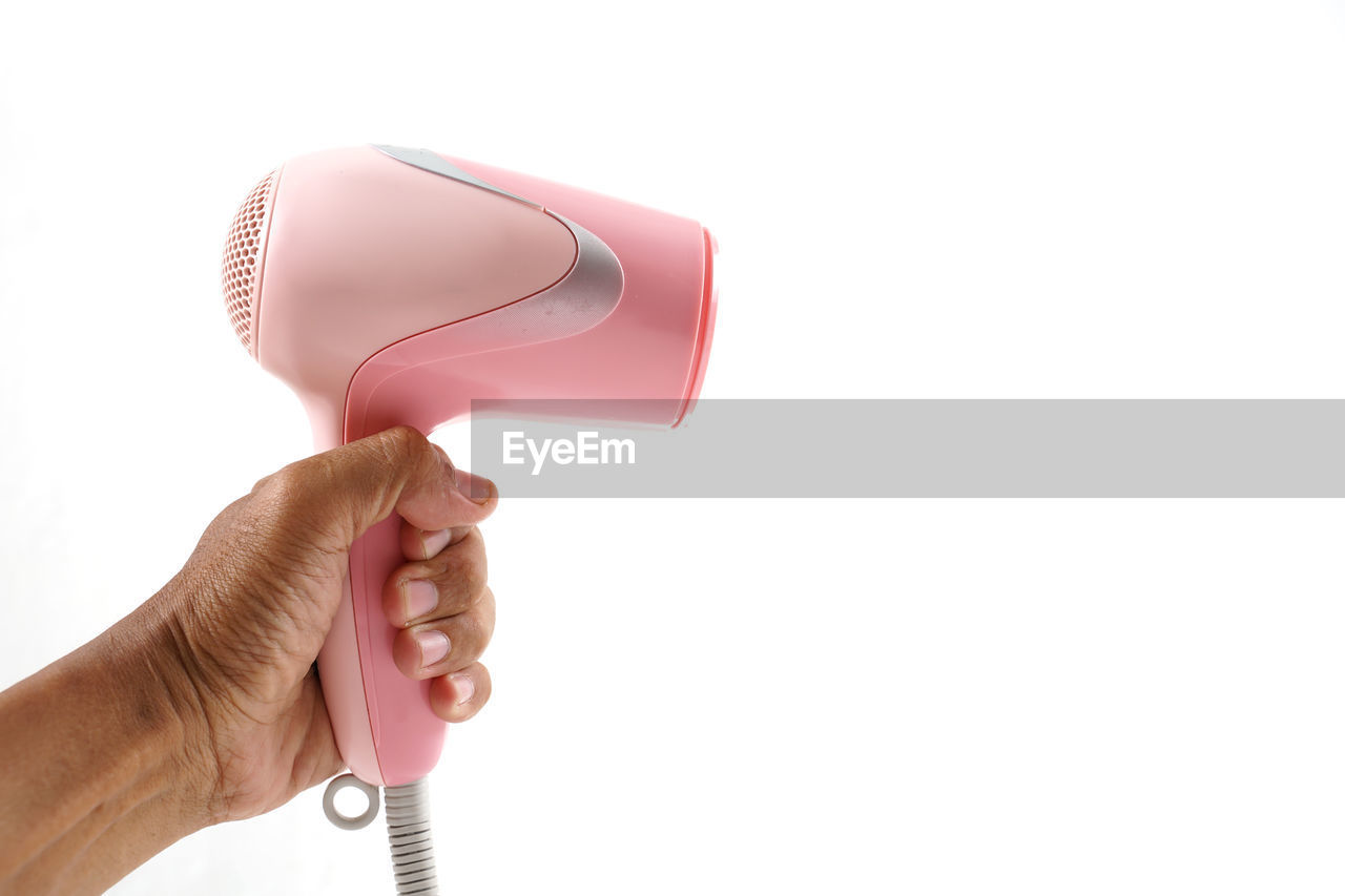 Close-up of hand holding hair dryer against white background