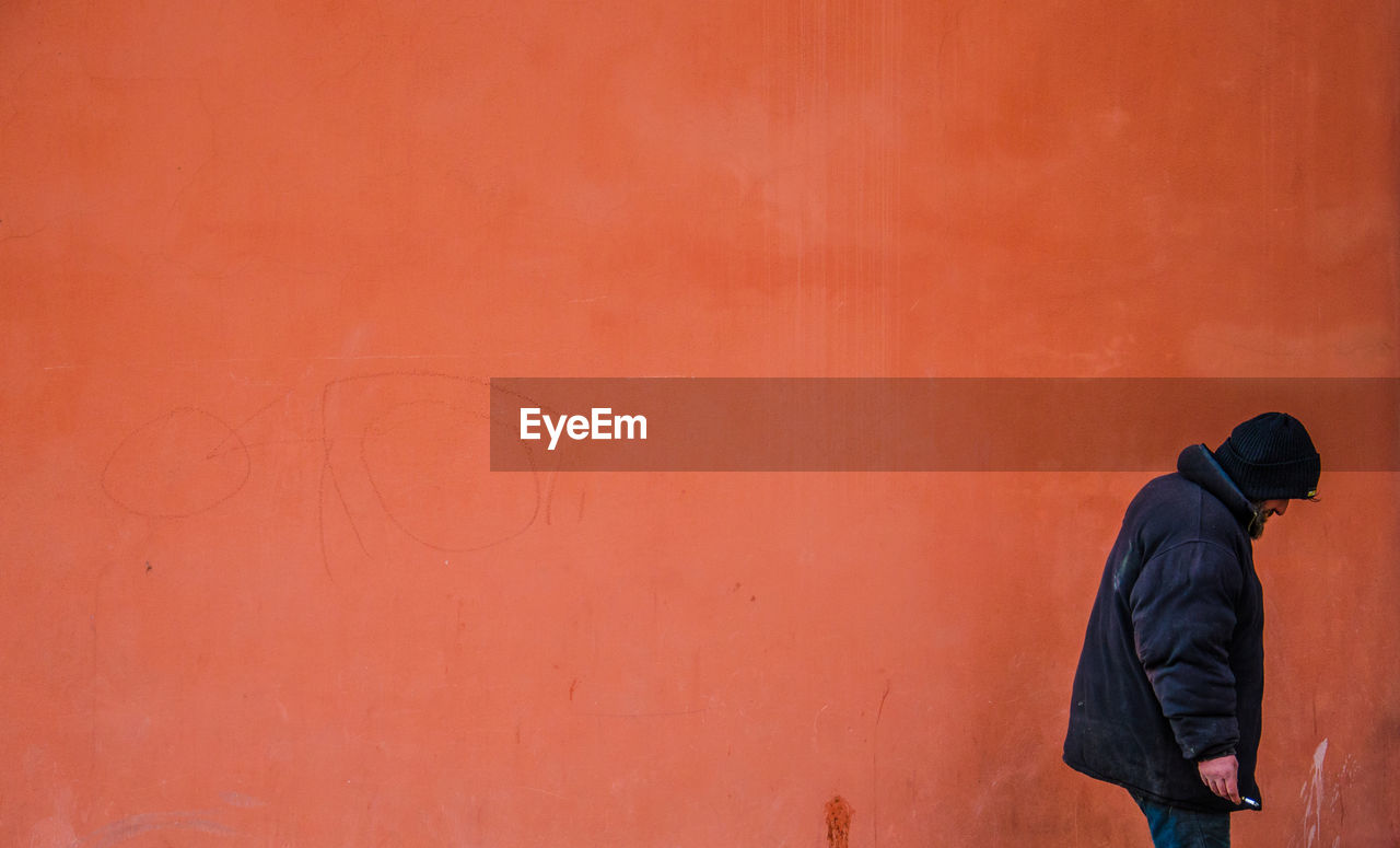 Man standing against orange wall