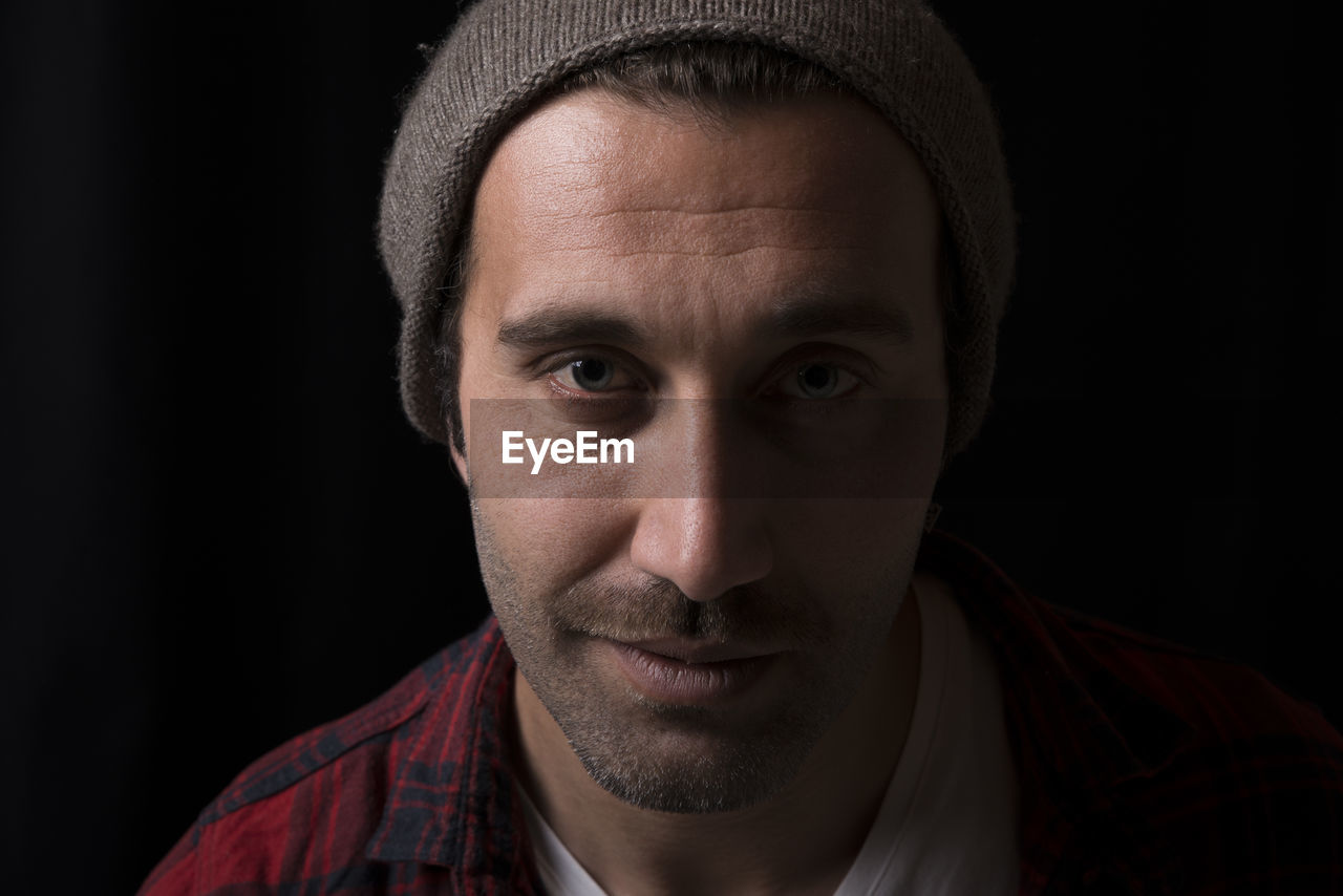 Close-up portrait of handsome man against black background