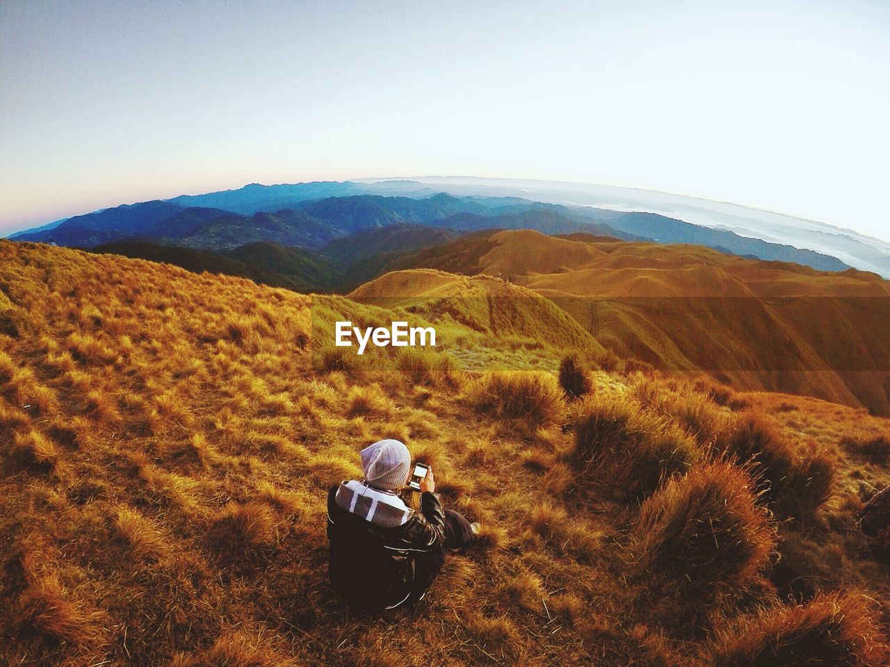 High angle view of man using phone on hill against sky