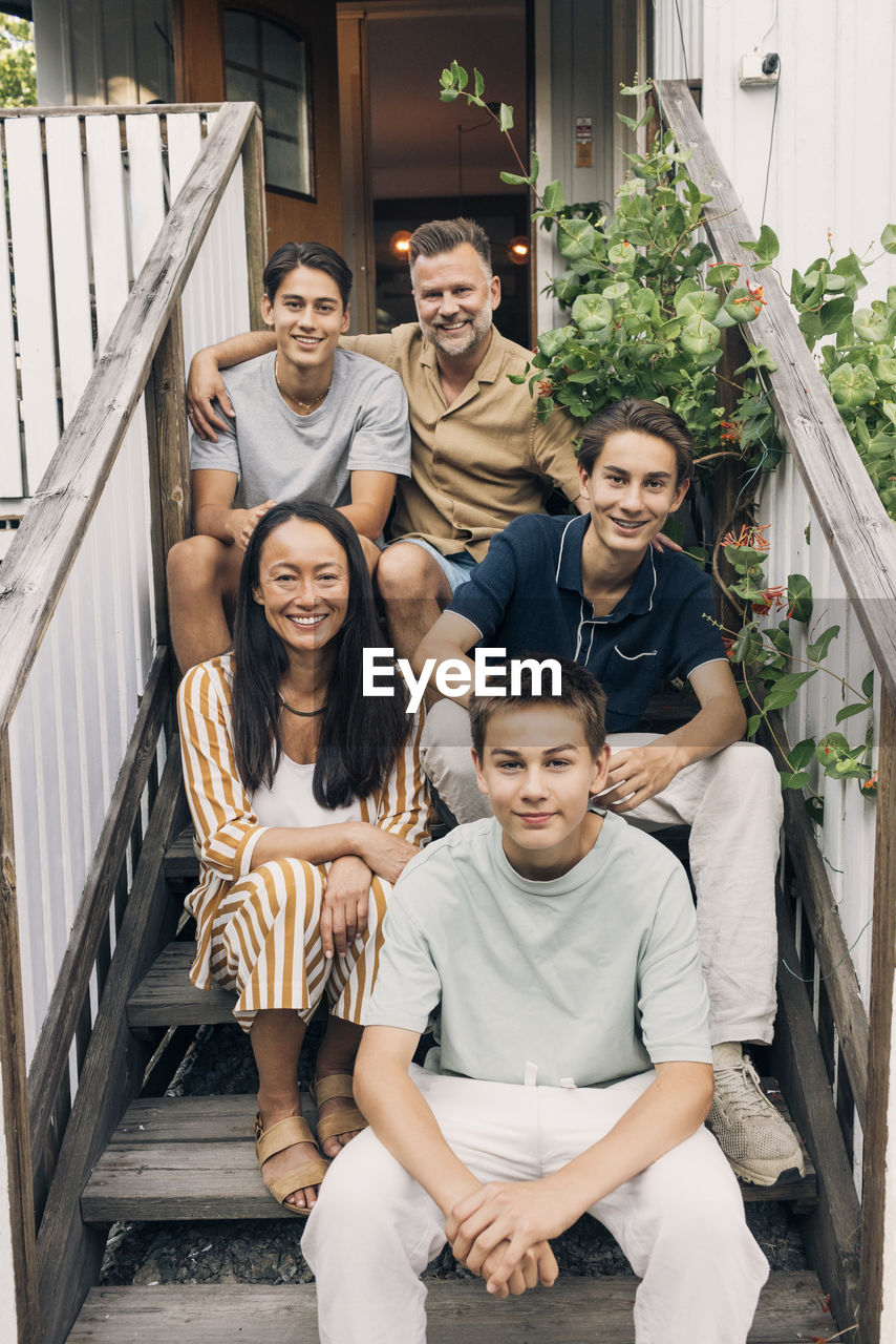 Portrait of multiracial family sitting on steps in front of house