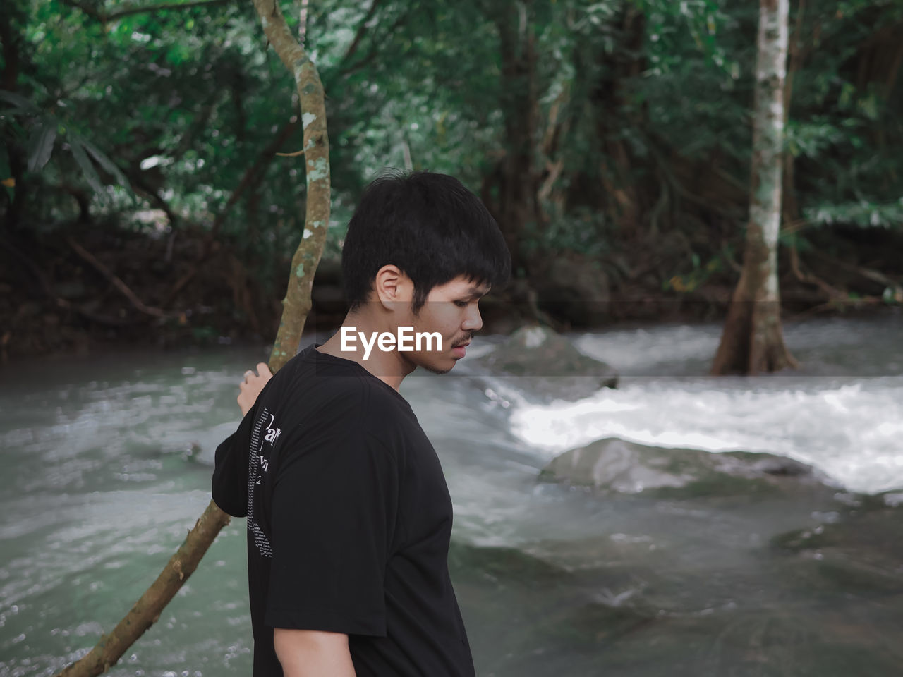 Side view of man standing by river in forest