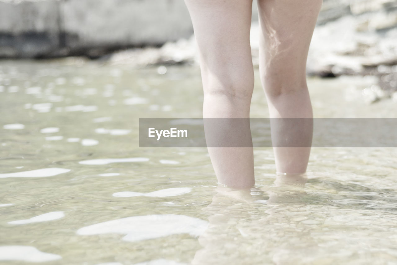 LOW SECTION OF PERSON STANDING ON BEACH