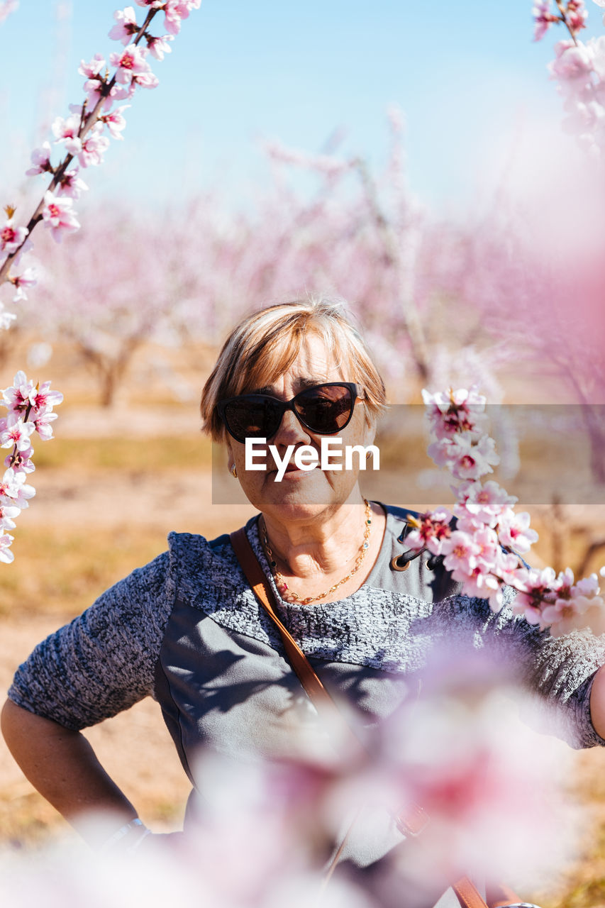 Portrait of woman standing by pink flowering plants