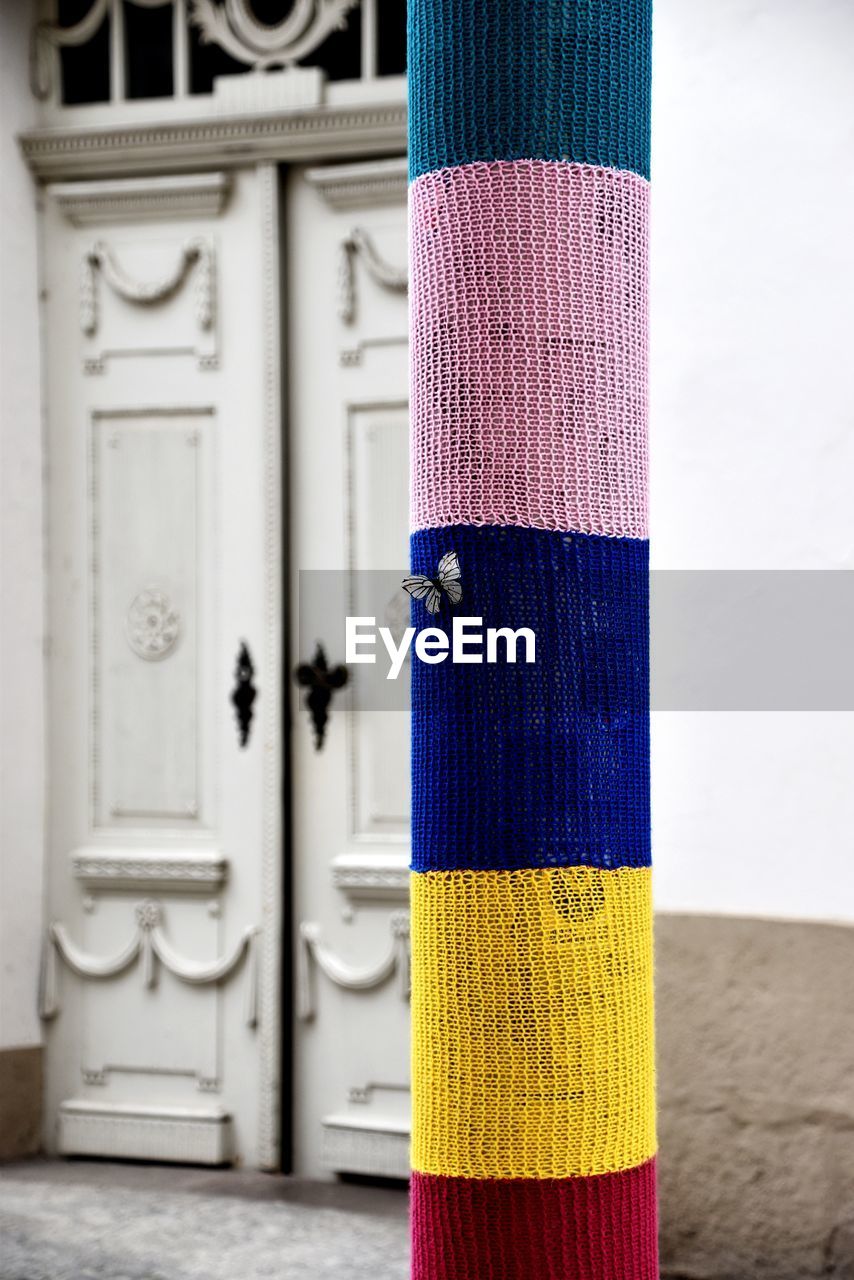 Close-up of colorful fabrics wrapped on pole against house