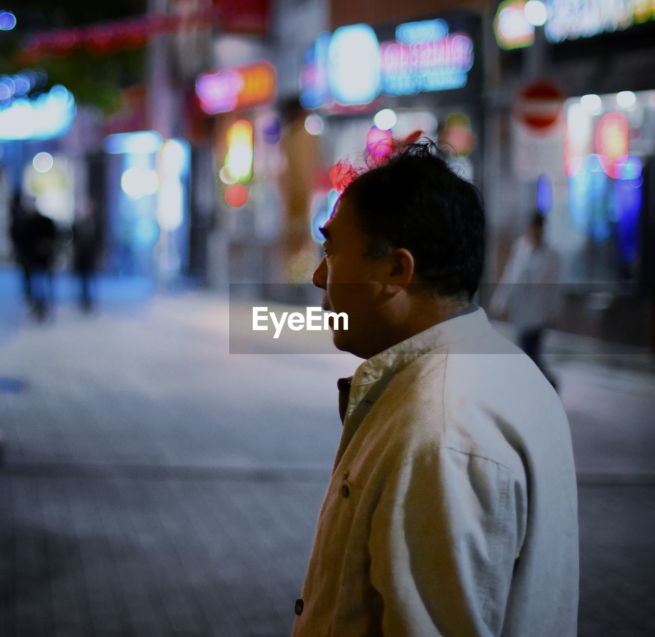 SIDE VIEW OF WOMAN IN ILLUMINATED CITY AT NIGHT