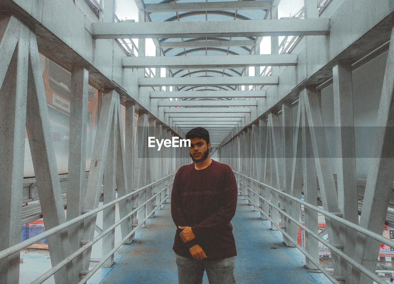 Portrait of young man standing on covered bridge