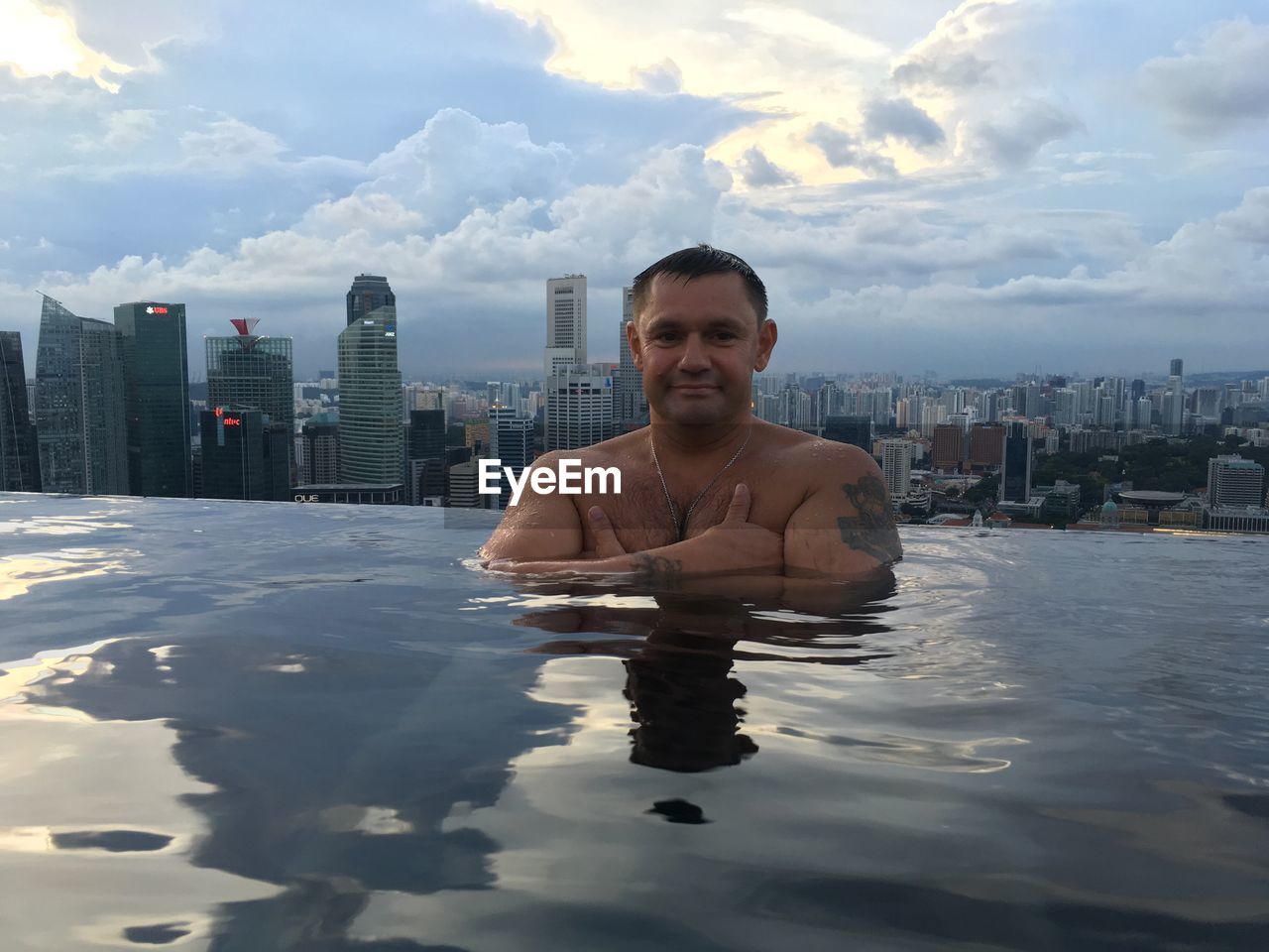 Portrait of man in infinity pool against city