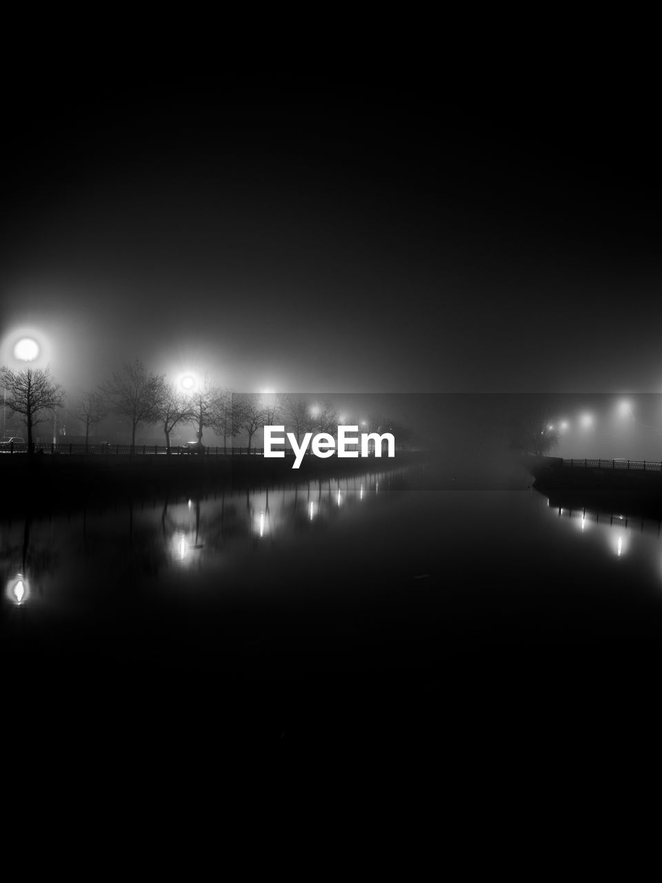 Reflection of street lights in canal against clear sky at night