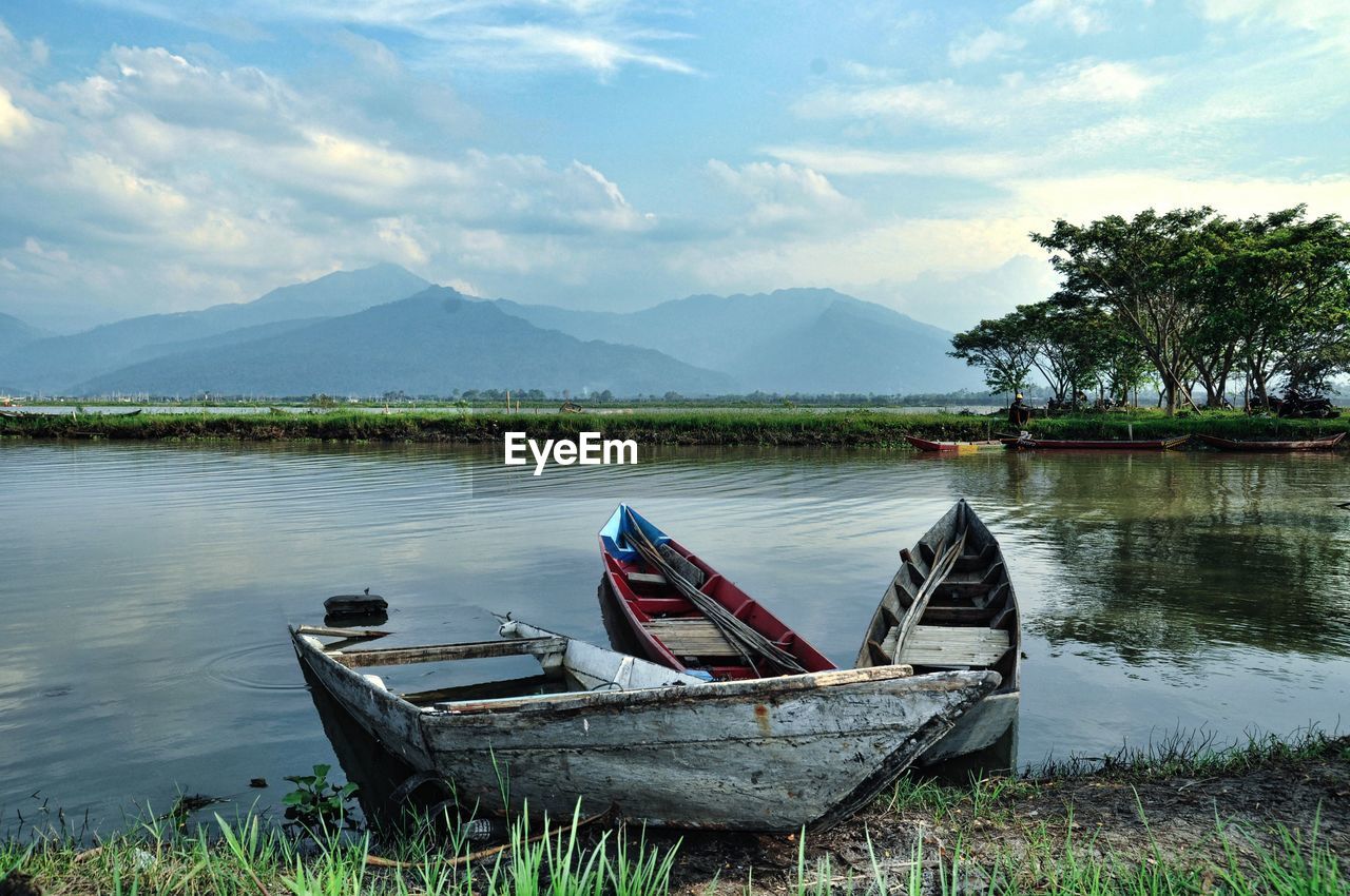 FISHING BOAT MOORED AT LAKE AGAINST SKY
