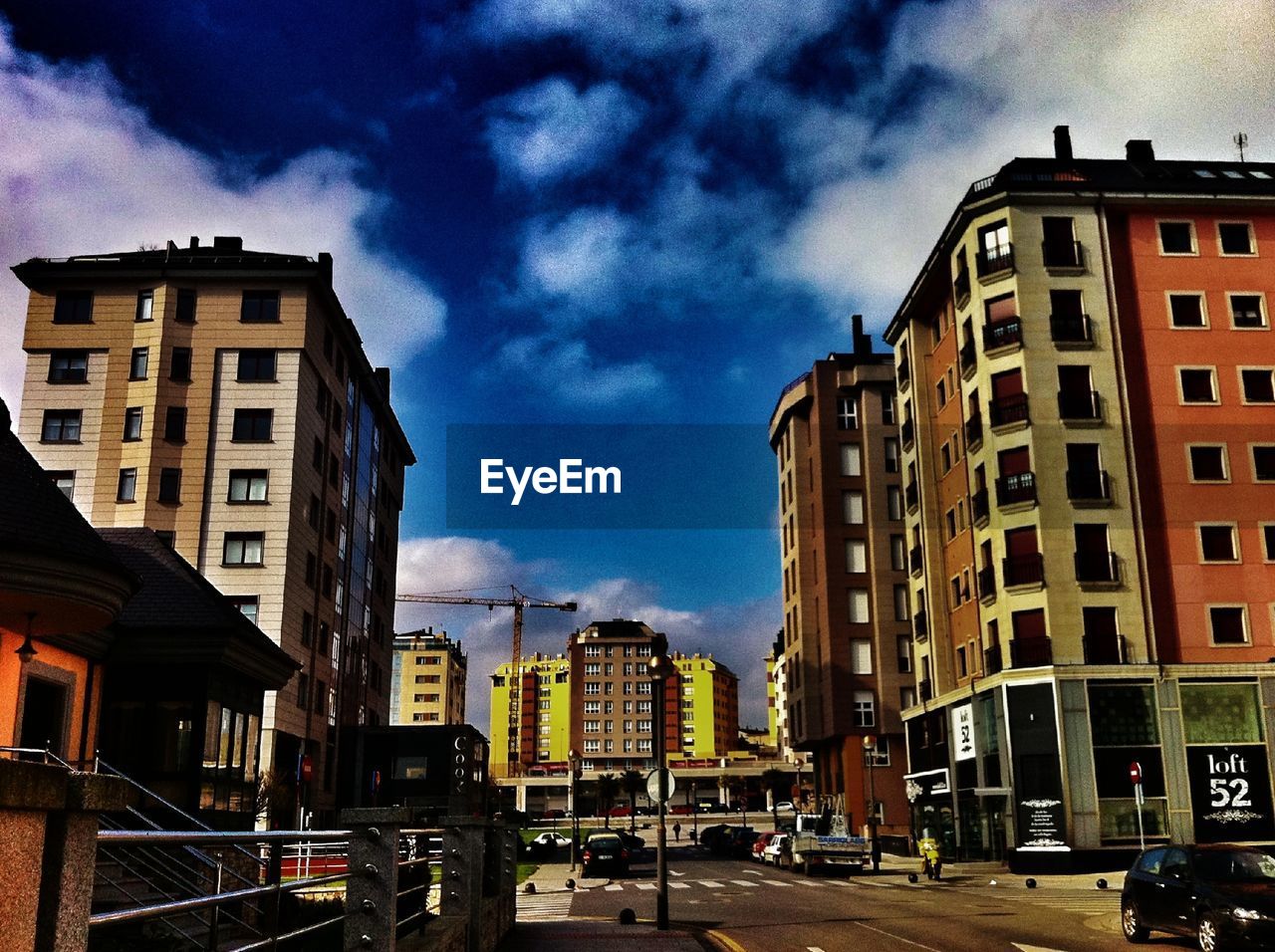 CARS ON ROAD BY BUILDINGS AGAINST SKY