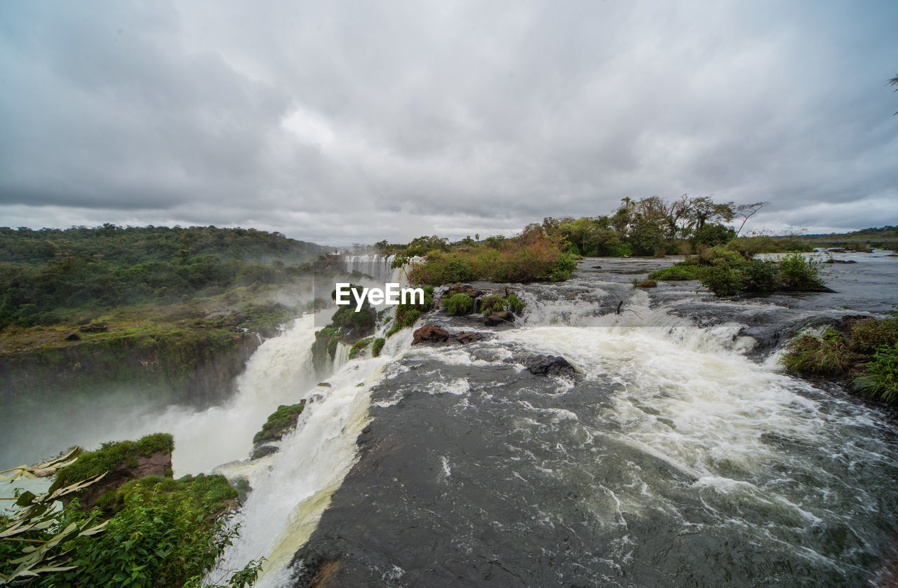 SCENIC VIEW OF WATERFALL AGAINST SKY DURING SUNSET