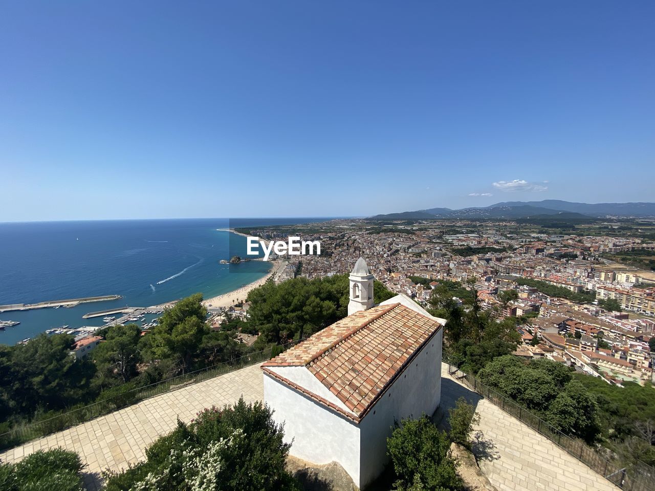 High angle view of townscape by sea against clear blue sky