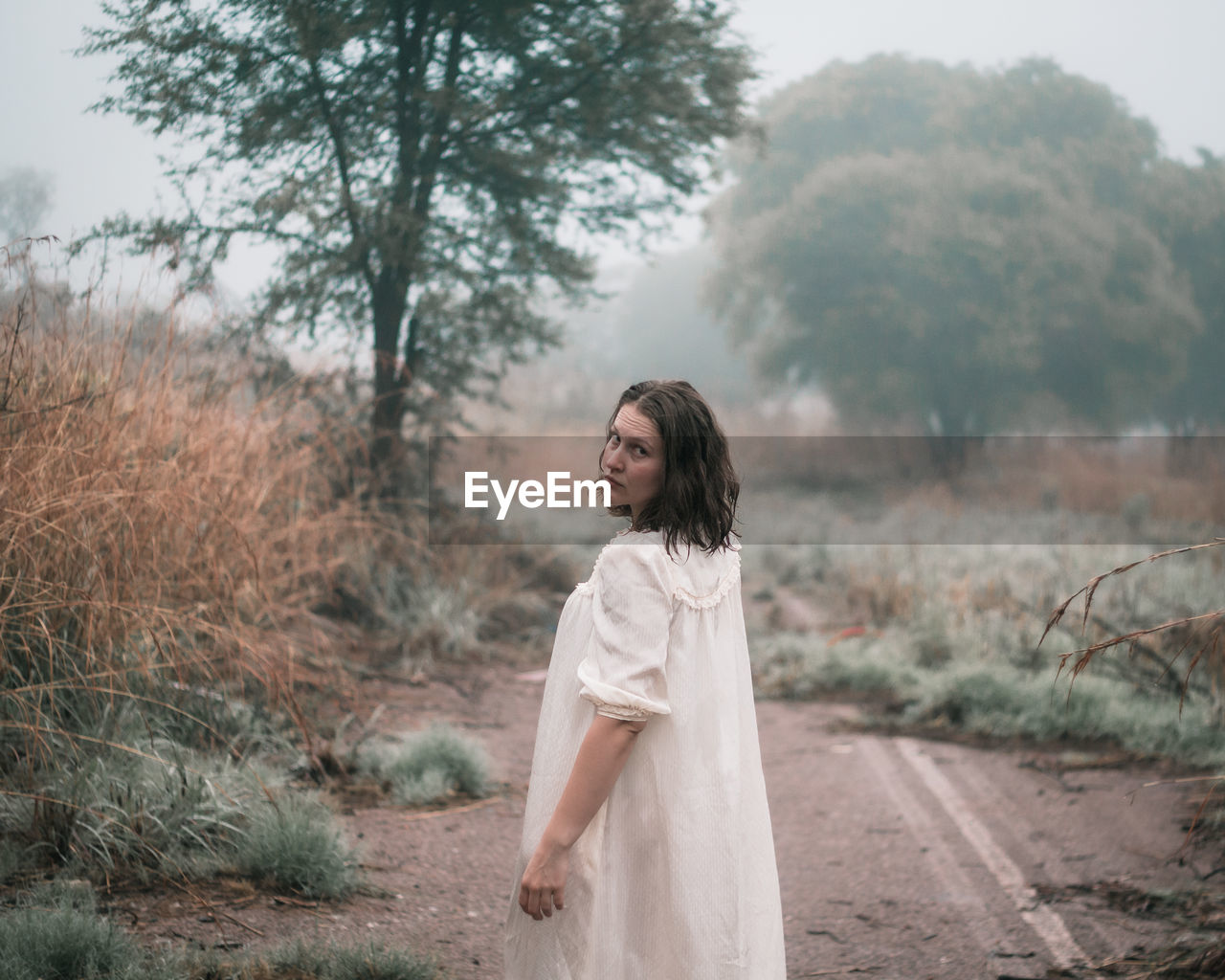 Woman in misty woods looking back. 