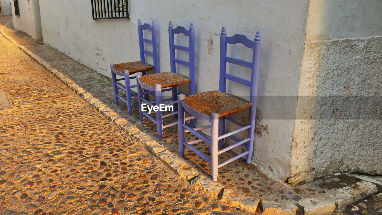 EMPTY CHAIRS AGAINST WALL AND OLD BUILDING