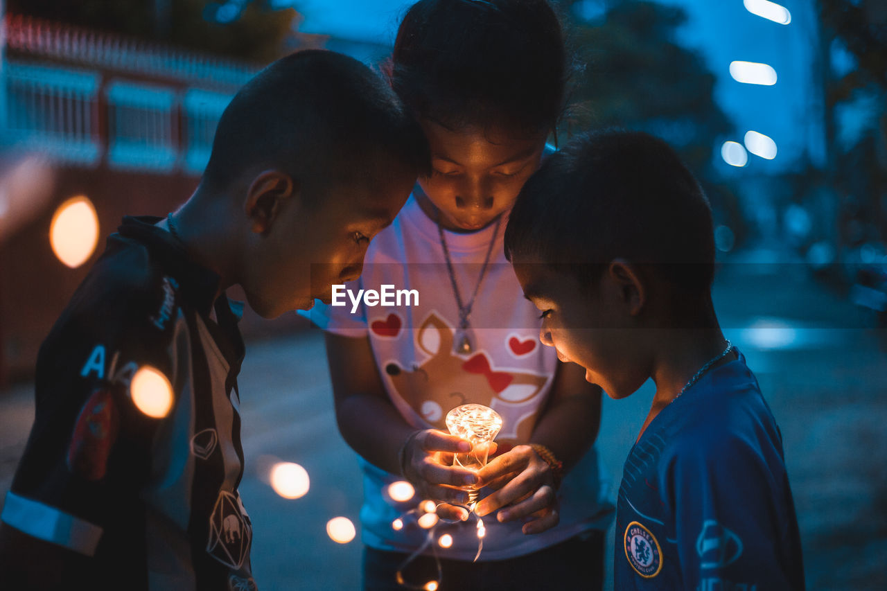 HIGH ANGLE VIEW OF FRIENDS HOLDING ILLUMINATED LIGHT