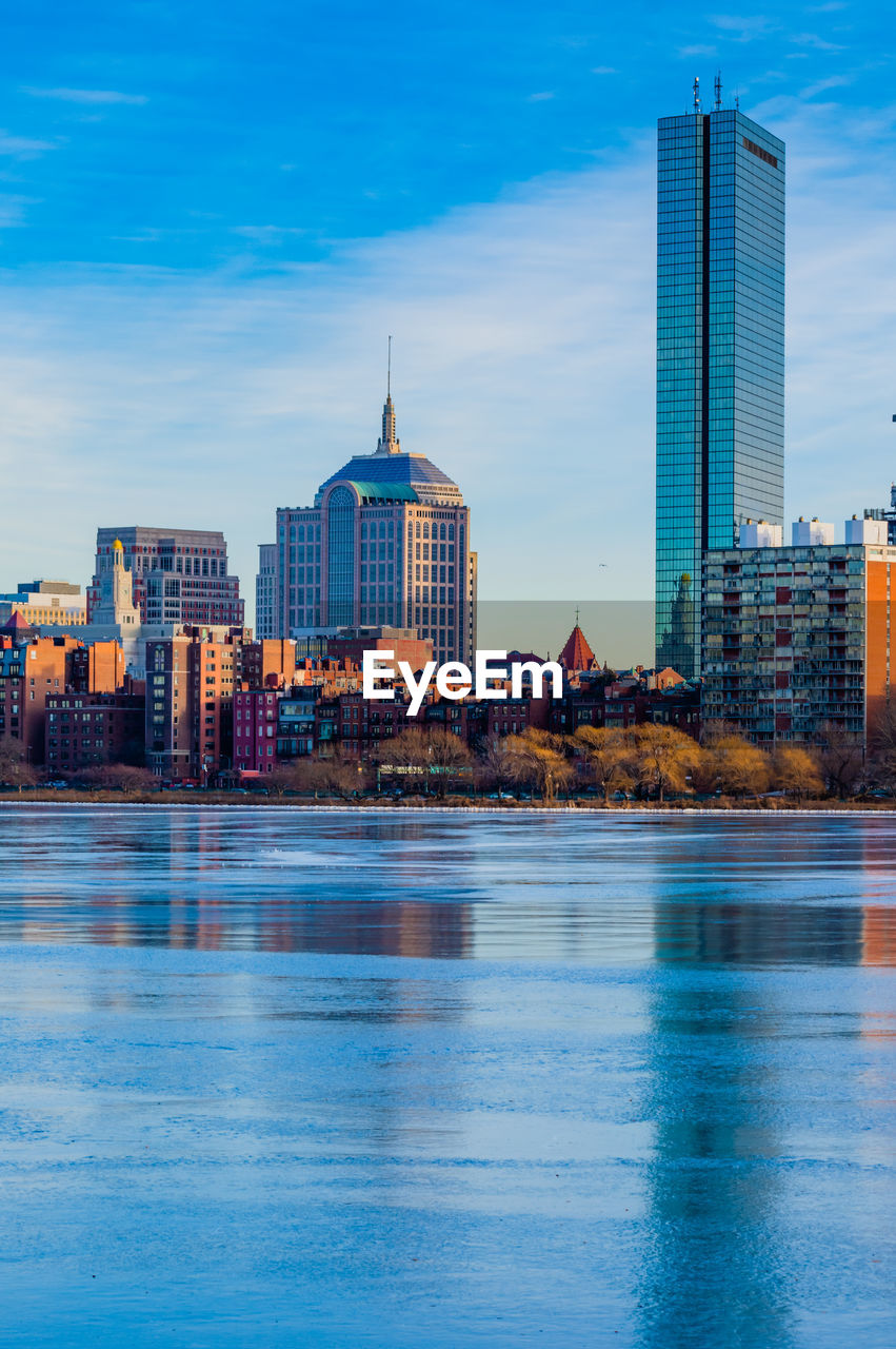 Buildings by river against sky