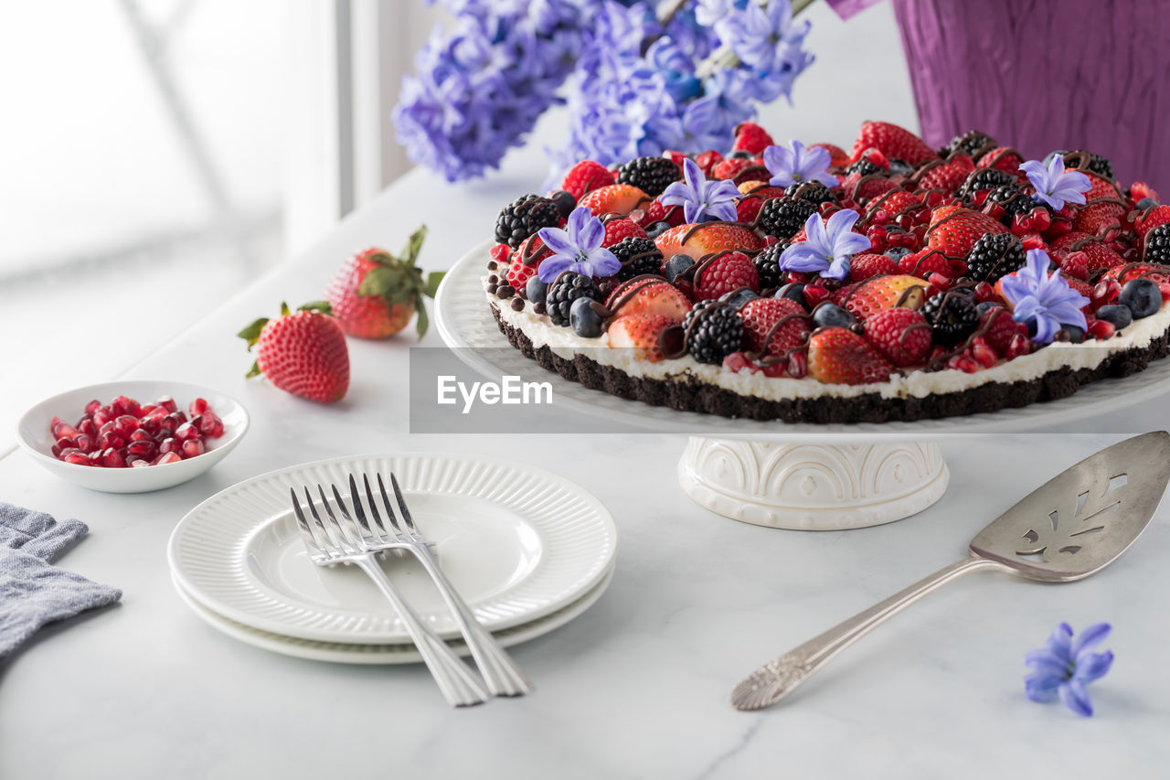 A delicious homemade mixed berry cheesecake tart with a chocolate cookie base.