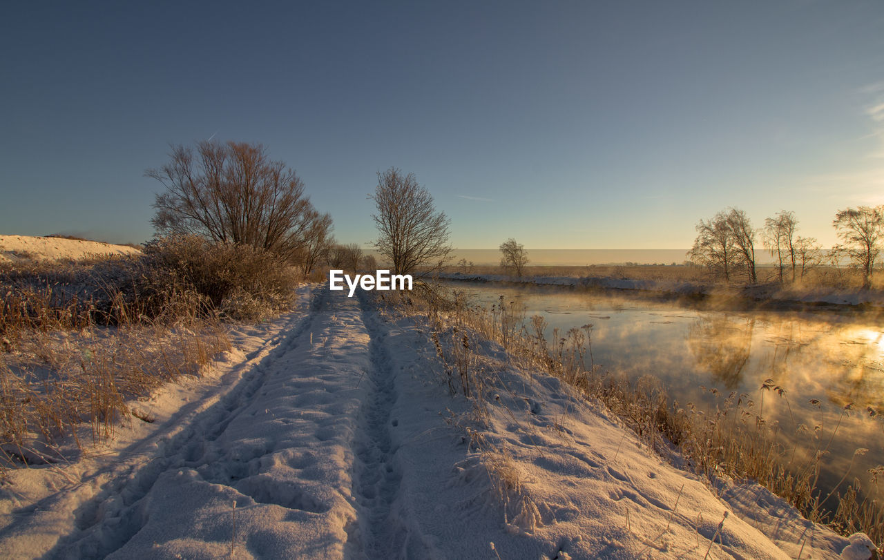 Snow covered field against sky during winter