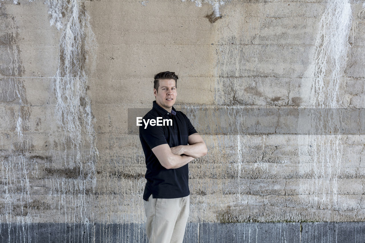 Portrait of mature man standing by wall