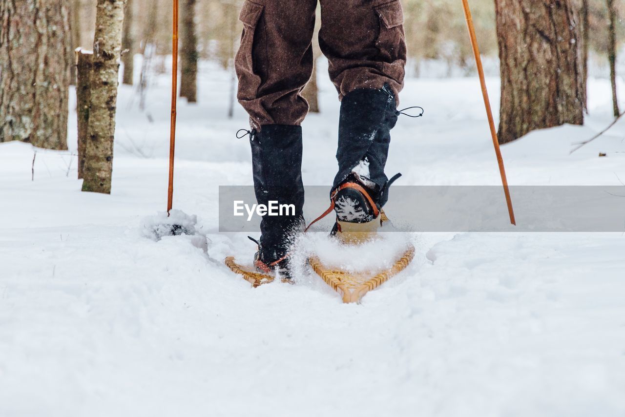 Low section of man walking on snow