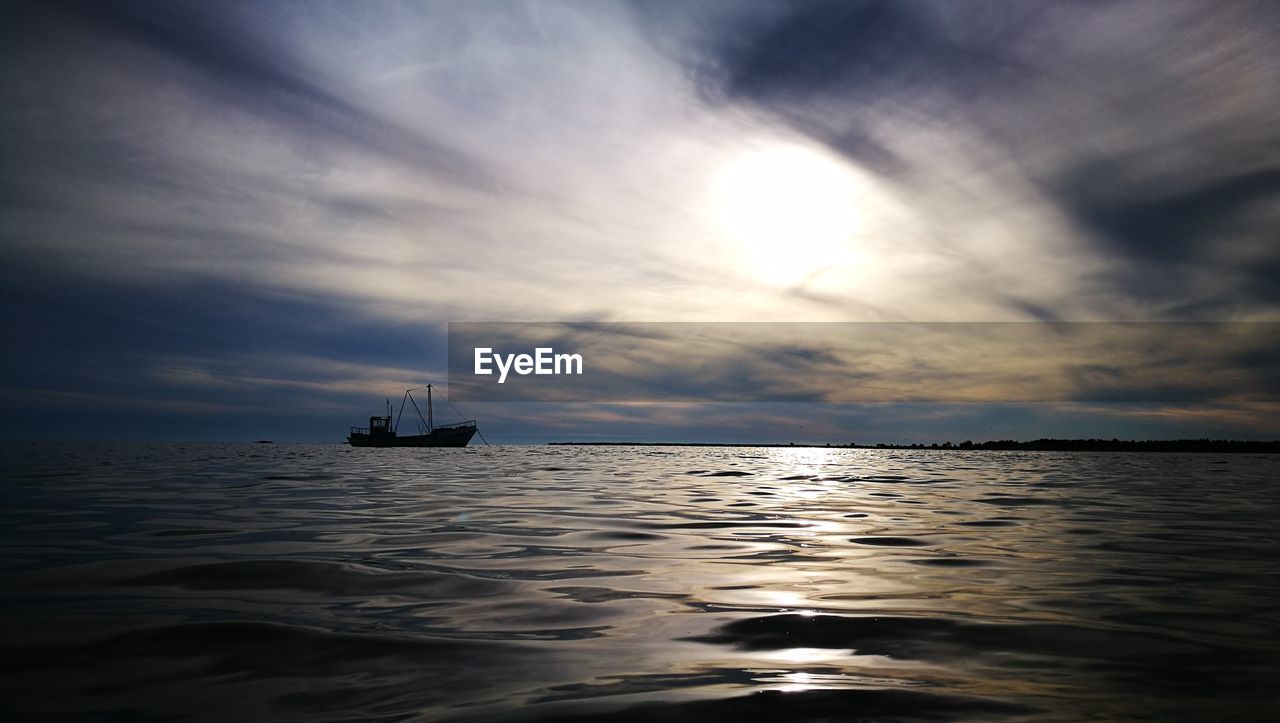 BOAT SAILING ON SEA AGAINST SKY DURING SUNSET