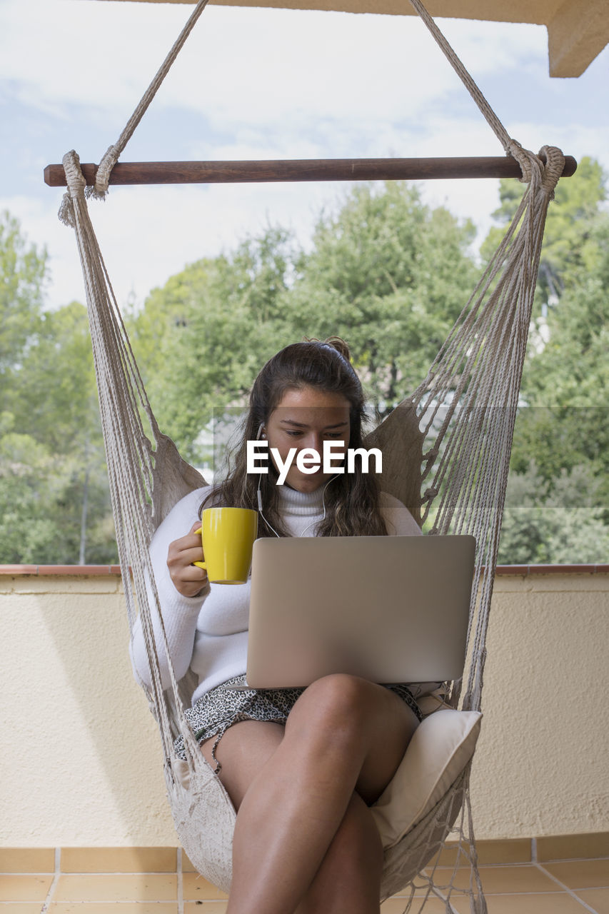 Midsection of woman using laptop while sitting outdoors