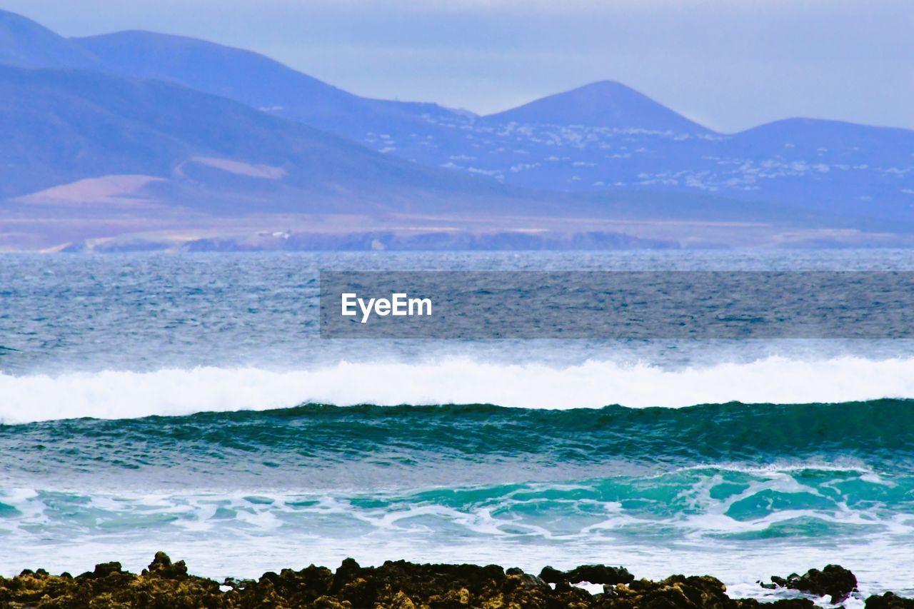 water, sea, scenics - nature, mountain, land, beauty in nature, horizon, environment, landscape, ocean, nature, sky, shore, wave, beach, wind wave, no people, coast, travel destinations, body of water, travel, motion, outdoors, sports, mountain range, tranquility, tranquil scene, day, cloud, blue, non-urban scene, tourism, rock, bay, animal wildlife, idyllic