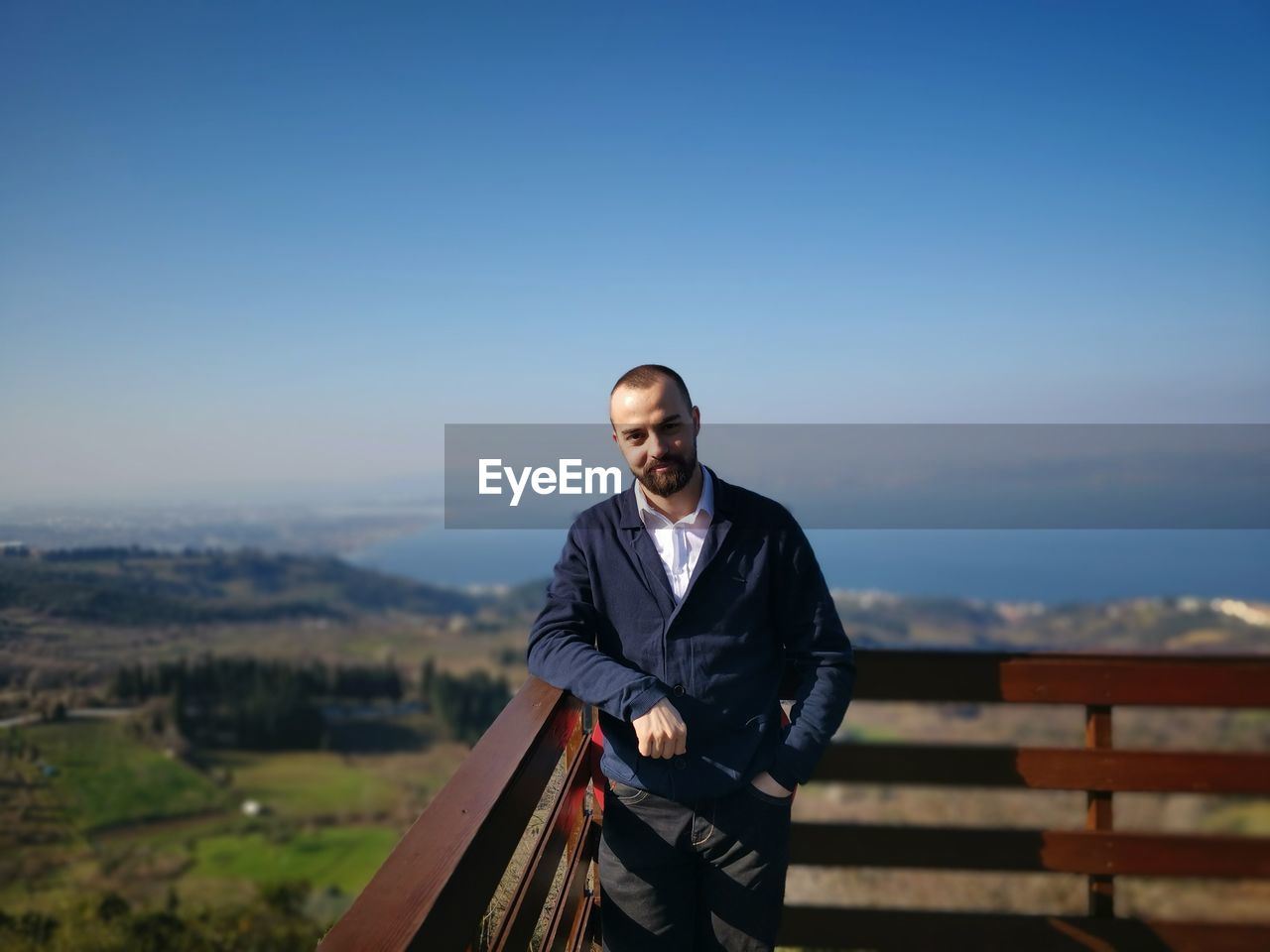 Portrait of young man standing against railing