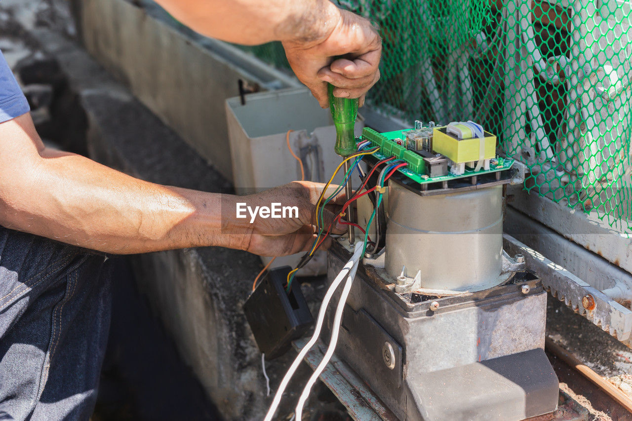 Electrician repairing home electronic gate system motor.