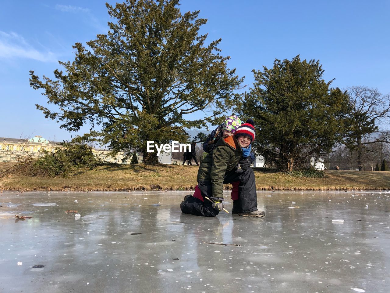 Portrait of smiling brothers on frozen lake against trees