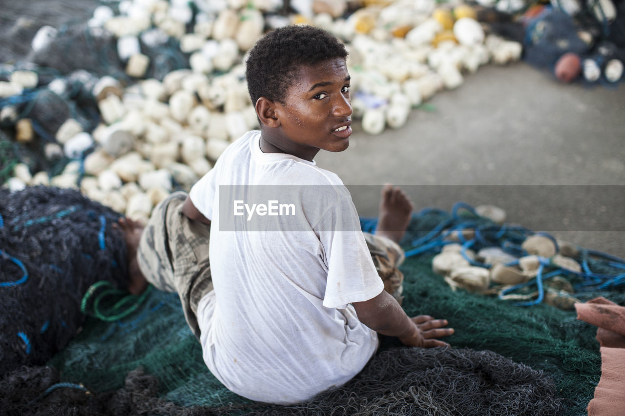 Portrait of teenage boy sitting on fishing net