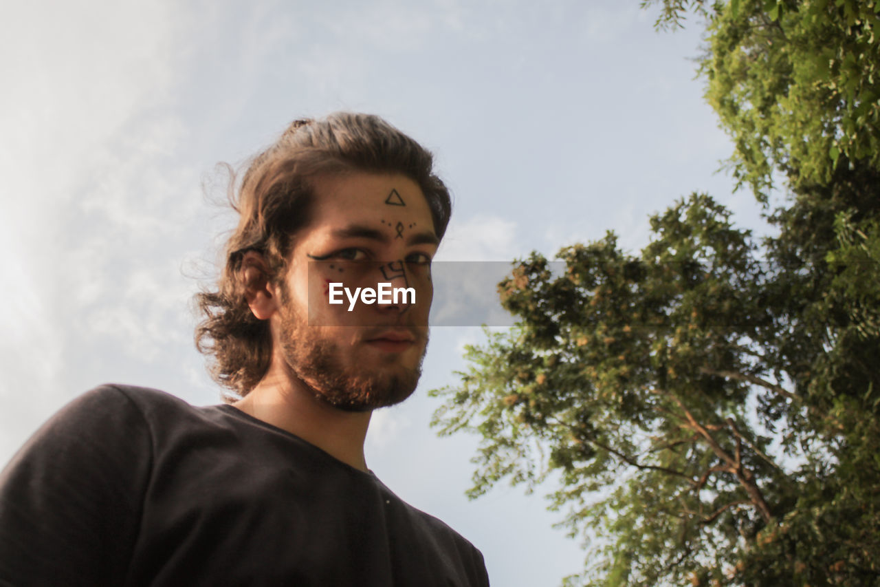 Portrait of young man looking away against sky